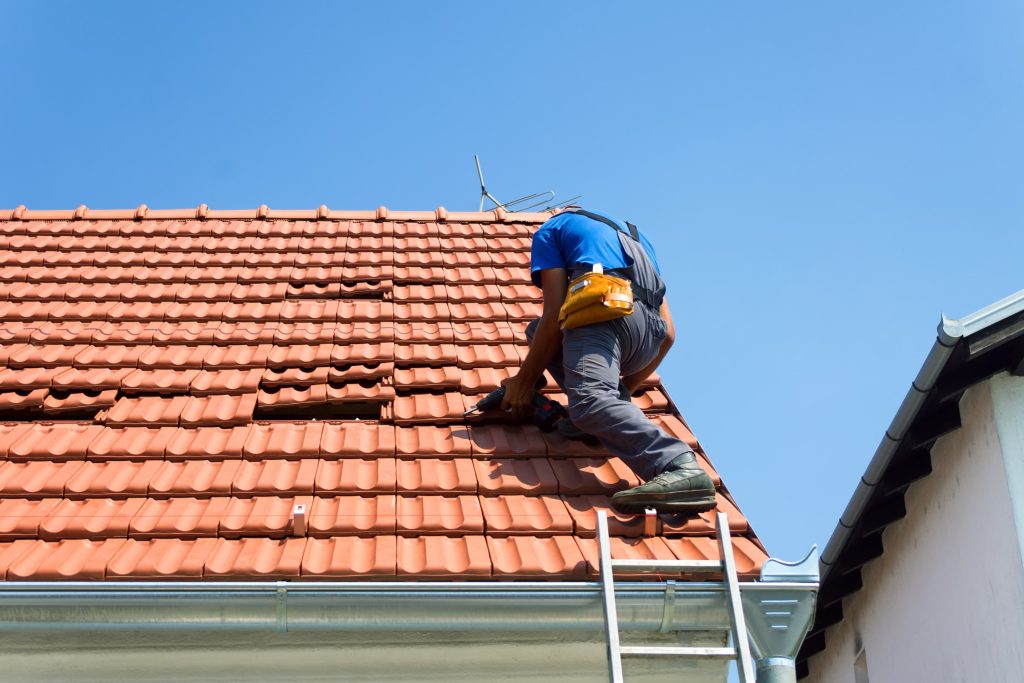 roofer on roof replacing tiles